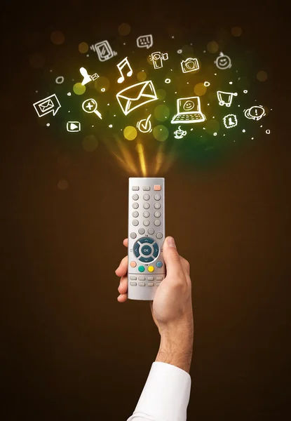 Hand with remote control and social media icons — Stock Photo, Image