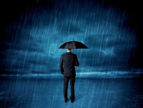 Business man standing in rain with an umbrella — Stock Photo, Image