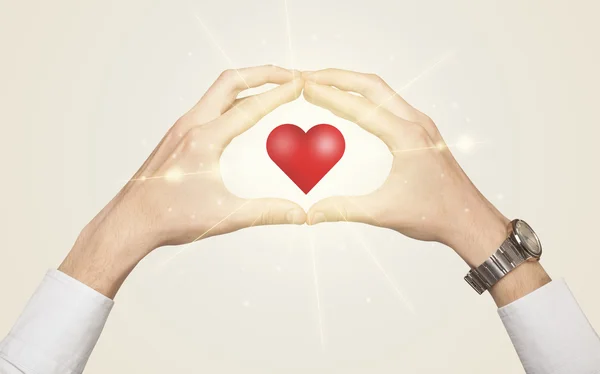 A kezek ragyogó szívű alakot teremtenek. — Stock Fotó