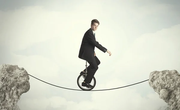 Храбрый бизнесмен ездит на моноцикле между скалами — стоковое фото