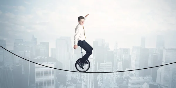 Brave guy riding a monocycle on a rope above cityscape — Stock Photo, Image