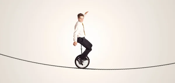 Экстремальный бизнесмен катается на моноцикле по веревке — стоковое фото