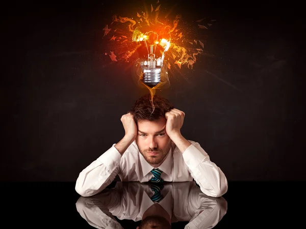 Businessman sitting under a blowing idea bulb — Stock Photo, Image