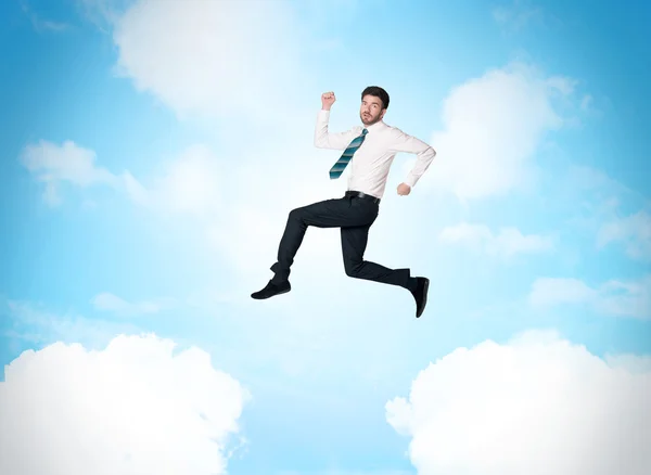 Деловой человек, прыгающий через облака в небе — стоковое фото