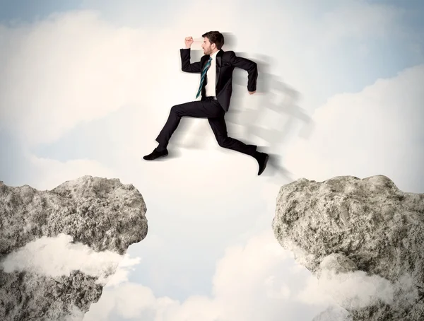 Happy business man jumping over a cliff — Stock Photo, Image