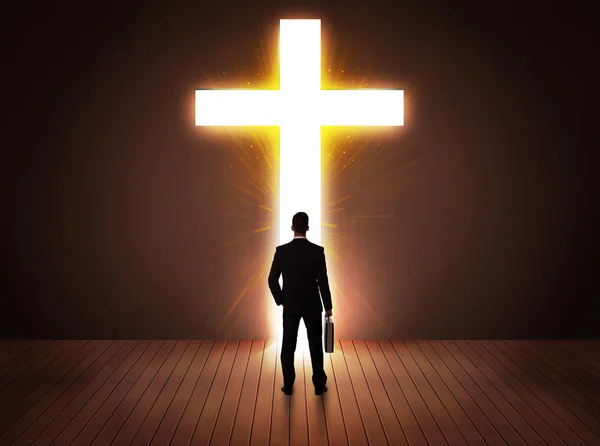Человек смотрит на яркий знак креста — стоковое фото