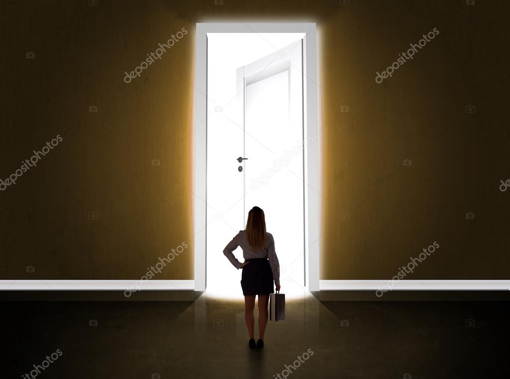 Business woman looking at big bright opened door