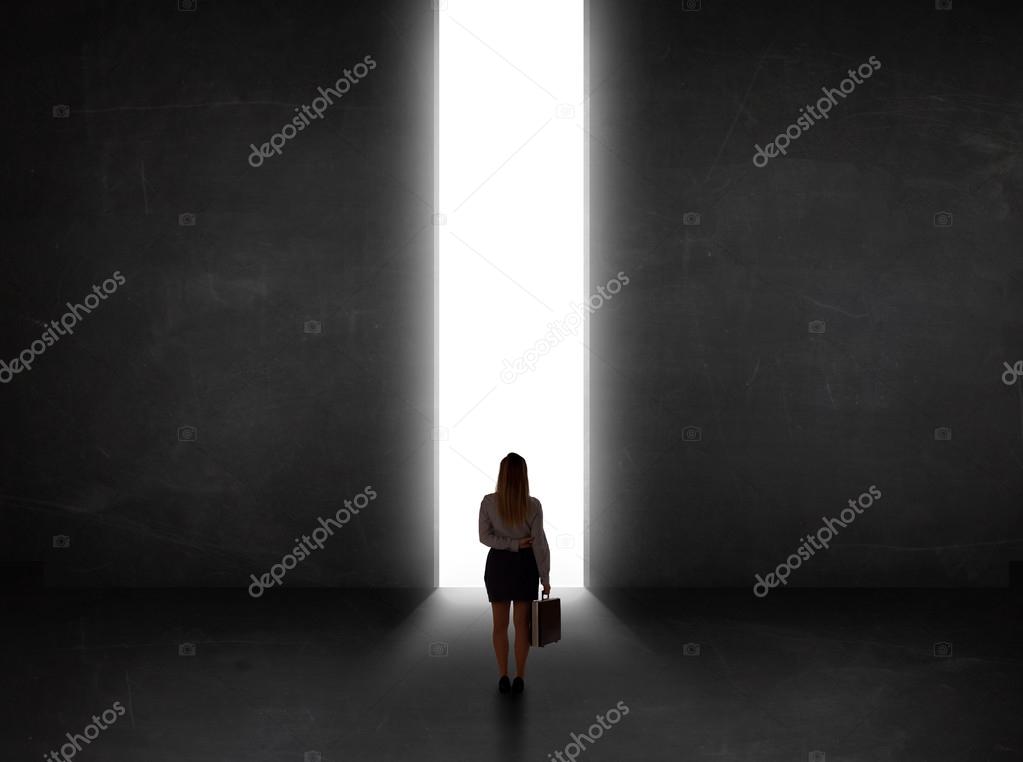 Business person looking at wall with light tunnel opening 