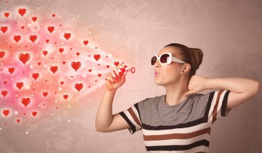 Güzel genç kız kırmızı kalp sembolleri üflüyor. 