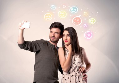 Mutlu çift gülen yüzle selfie çekiyor.