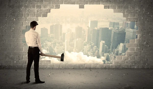 Hombre de negocios golpeando la pared con martillo en la vista de la ciudad — Foto de Stock