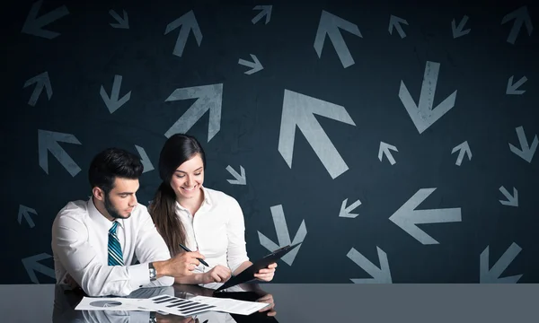 Business couple with arrows in background — Stock Photo, Image