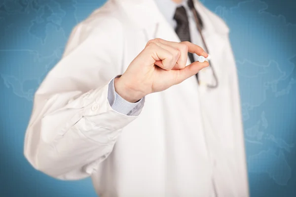 Doctor in white holding a pill — Stock Photo, Image