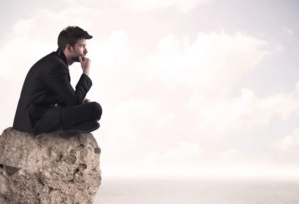 Business man sitting on stone edge — Stock Photo, Image