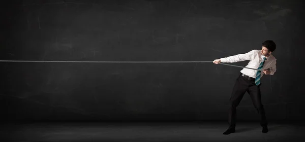 Бізнесмен тягне мотузку на сірому фоні — стокове фото
