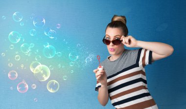 Mavi arka planda renkli kabarcıklar çıkaran güzel bayan.