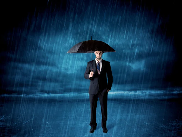 Hombre de negocios de pie bajo la lluvia con un paraguas —  Fotos de Stock