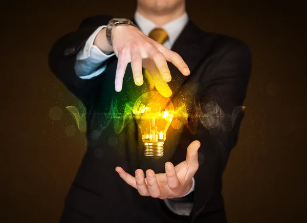 Бизнесмен держит лампочку — стоковое фото