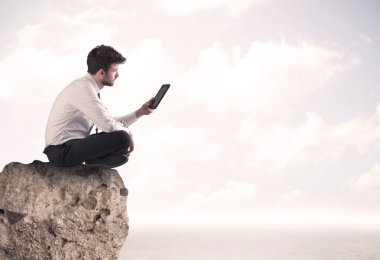 İş adamı taşın üstünde oturuyor.