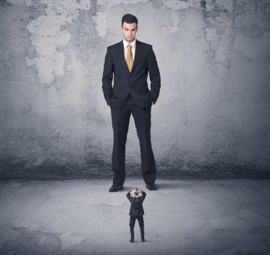 Büyük işletme zorbası küçük iş arkadaşına bakıyor.