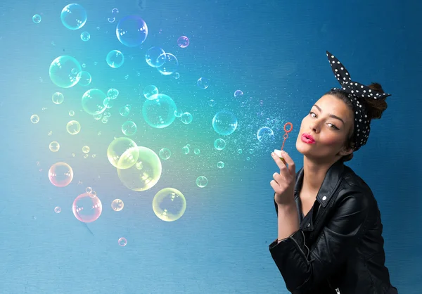 Mooie dame blazen kleurrijke bubbels op blauwe achtergrond — Stockfoto