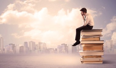 Şehrin üstündeki kitap yığınında oturan adam.
