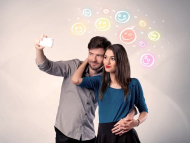 Mutlu çift gülen yüzle selfie çekiyor.