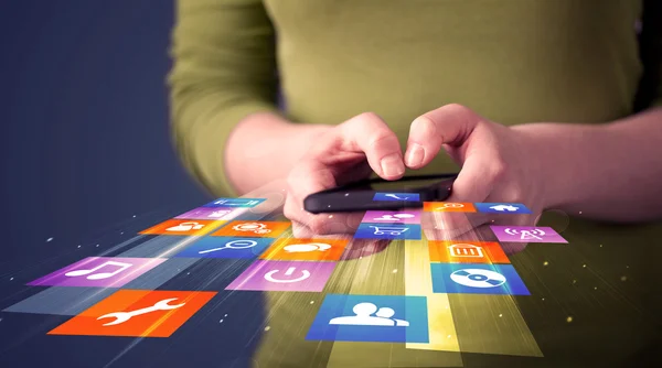 Mulher segurando telefone inteligente com ícones de aplicação coloridos — Fotografia de Stock