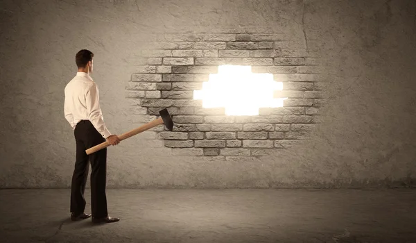 Business man hitting brick wall with hammer and opening a hole — Stock Photo, Image