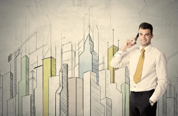 Businessman standing with drawn cityscape — Stock Photo, Image