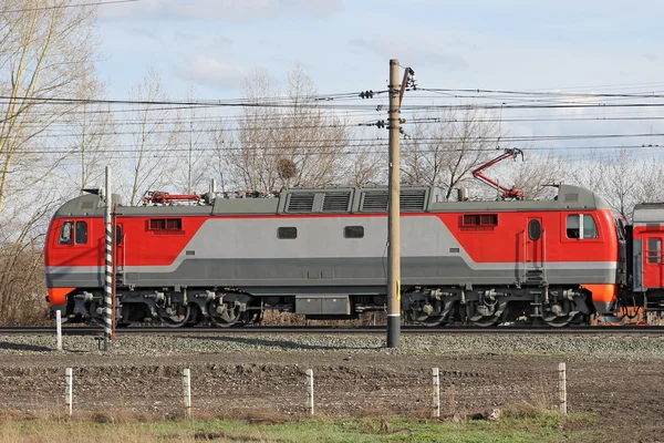 Červená lokomotiva na elektřinu, přichází po železnici. — Stock fotografie