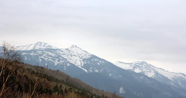 Cumes de montanha cobertos de neve e céu nublado . — Fotografia de Stock