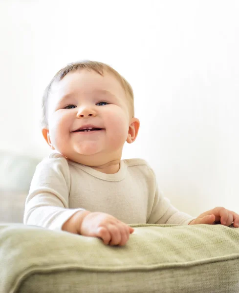 Bebê feliz joga no sofá — Fotografia de Stock