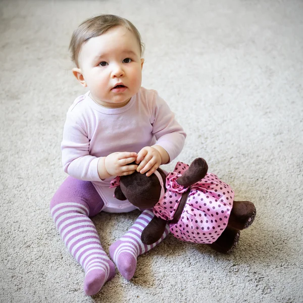 Menina bonita sentada no chão com urso de brinquedo — Fotografia de Stock