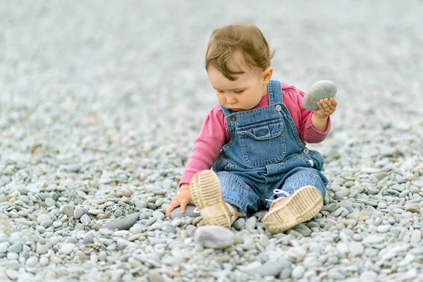 Çakıl taşları ile sahilde oynarken kız bebek