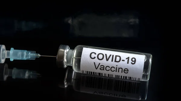 Coronavirus vaccine on black close-up, syringe and bottle with vaccine for COVID-19 cure. Concept of corona virus drug, treatment, injection, medical shot and clinical trial during COVID pandemic.