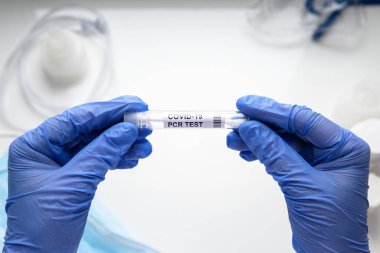 Coronavirus örnek toplama kiti doktorun ellerinde, beyaz arka plandaki laboratuvarda COVID-19 PCR testi tüpü. COVID salgını sırasında korona virüsü teşhisi, tıbbi test ve tedavi kavramı.
