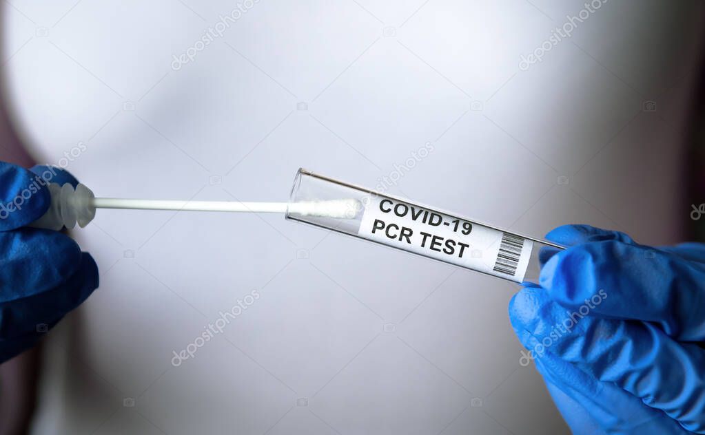 PCR test to COVID-19 in doctor hands close-up, woman in white holds coronavirus swab collection kit. Concept of corona virus diagnostics, medical testing, cure and treatment during pandemic.