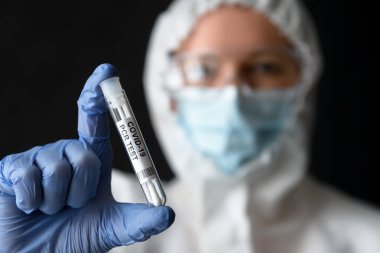 Doktorun elinde Coronavirus örnek toplama kiti, tıbbi PPE kıyafetli hemşire COVID-19 PCR testi tüpü tutuyor. Salgın sırasında korona virüsü tanısı, testi, karantinası ve tedavisi kavramı.
