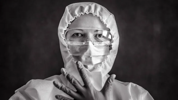Doctor in personal protective equipment (PPE), woman wearing medical glasses and face mask, portrait of nurse in professional suit due to COVID-19 coronavirus. Hospital and COVID pandemic concept.