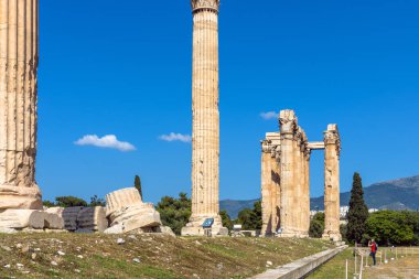 Yunanistan, Atina 'daki Zeus tapınağı. Atina 'nın ünlü anıtı ve simgesidir. Turist kız, Atina şehir merkezindeki Antik Yunan harabelerine, klasik binaların büyük sütunlarına bakıyor. Seyahat kavramı.