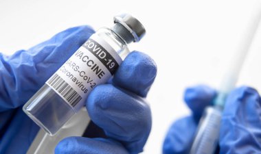 Laboratuvarda ya da hastanede beyaz arka planda COVID-19 aşısı. Coronavirus aşı şişeleri ve şırınga doktorun ellerinde. COVID salgını sırasında korona virüsü aşısı, aşı ve enjeksiyon kavramı.