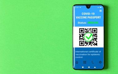 Digital health passport of COVID-19 vaccination in mobile phone on green background, passport app in smartphone for travel. Coronavirus vaccine certificate as proof of corona virus immunization.