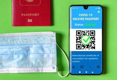 Health passport of COVID-19 vaccination in mobile phone, mask and tourist passport. Vaccine certificate app in smartphone for travel. Digital coronavirus immune pass. Corona virus and tourism concept