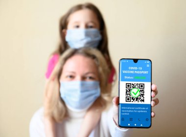 Health passport of COVID-19 vaccination in mobile phone, happy woman and kid hold smartphone with certificate app of immunization, digital coronavirus pass. Concept of corona virus, travel and family