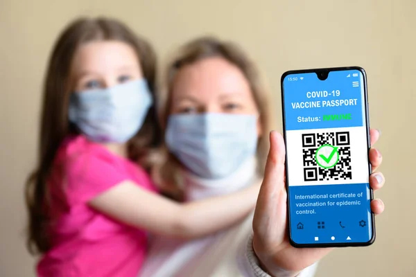 Health digital passport of COVID-19 vaccination in mobile phone, happy family hold smartphone with certificate app, coronavirus immunity passport. Concept of corona vaccine during COVID pandemic.
