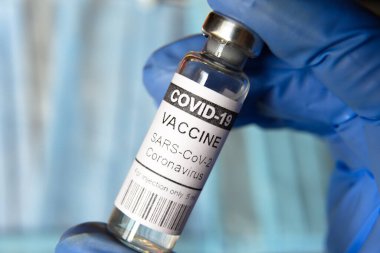 Coronavirus vaccine vial closeup, doctor holds bottle with COVID-19 vaccine for injection. Concept of corona virus vaccination, immunization and vaccine clinical trial during COVID pandemic.