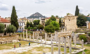 Atina - 6 Mayıs 2018: Turistler Atina, Yunanistan 'da Roman Agora' yı ziyaret ettiler. Atina şehir merkezindeki Plaka semtinde Antik Yunan harabelerinin panoraması. Eski Rüzgâr Kulesi sağda, Atina 'nın ünlü simgesi. 