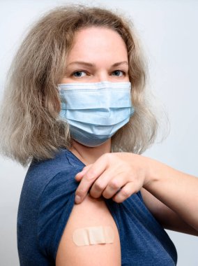 COVID-19 aşısı olduktan sonra, tıbbi maske takmış güzel bir kadının alçılı bir portresi. Koronavirüs aşısı, aşı alma, aşı vurulma ve korona virüsünü önleme kavramı