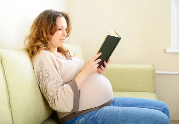 Söta gravida kvinna läser en bok hemma — Stockfoto